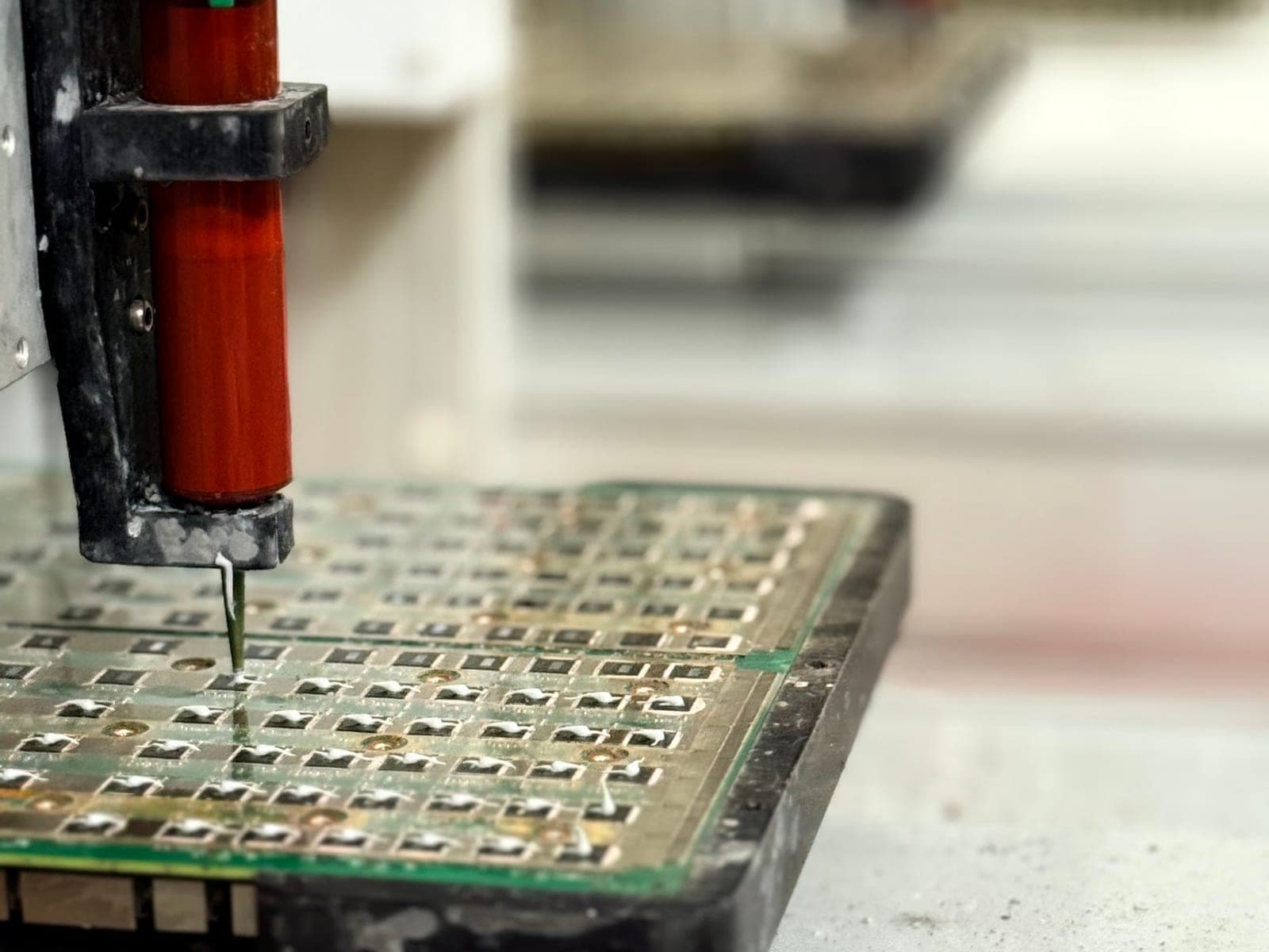 A dispensing head over a populated circuit board panel on the ACS electronics line